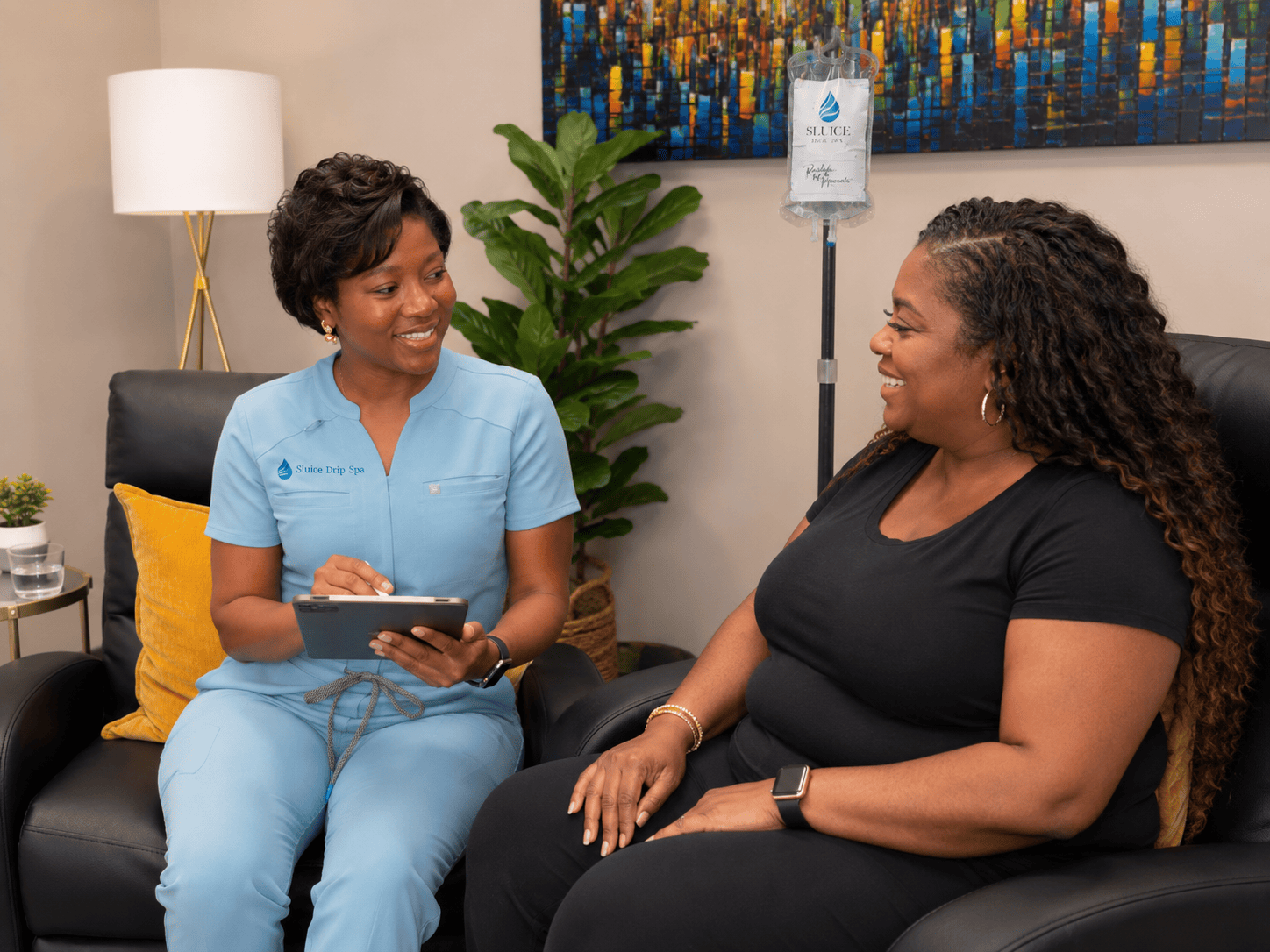 Lola Peterson, MPH, PA-C consulting with a client beside an IV infusion